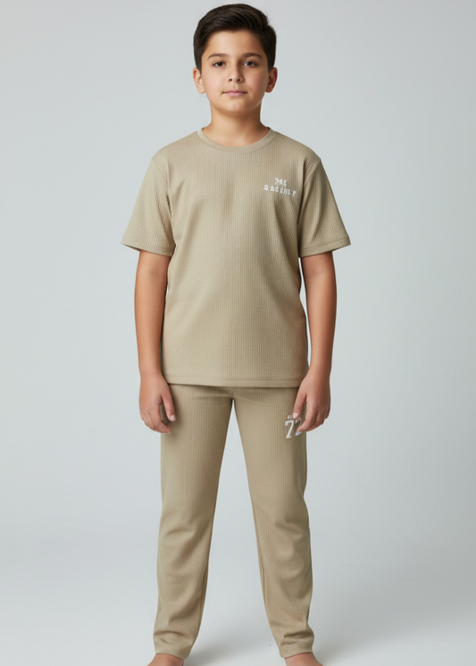 Child wearing a beige t-shirt and pants set on a white background